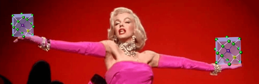 A still of Marilyn Monroe from the "Diamond's Are a Girl's Best Friend" performance, holding an illustration of a nitrogen vacancy center in each outstretched hand.
